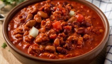 Easy homemade chili recipe: A bowl of homemade chili con carne, topped with melted cheese, sour cream, and green onions – a rich and hearty chili recipe.