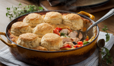 Easy chicken cobbler recipe in a rustic baking dish with golden biscuit topping and mixed vegetables