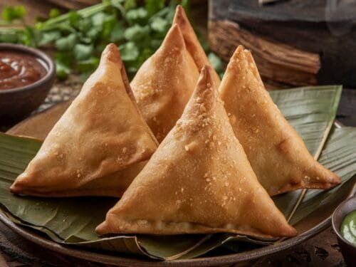 A plate of our crispy samosa recipe served with tamarind and mint chutneys.