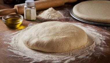 Freshly prepared pizza dough on a floured surface with ingredients around it.